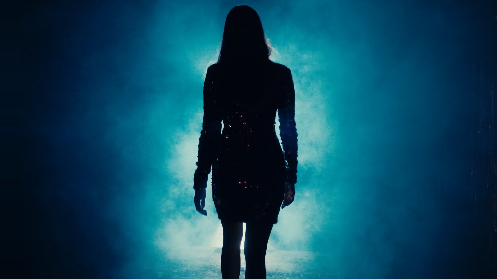 Film still: a woman silhouetted against blue haze