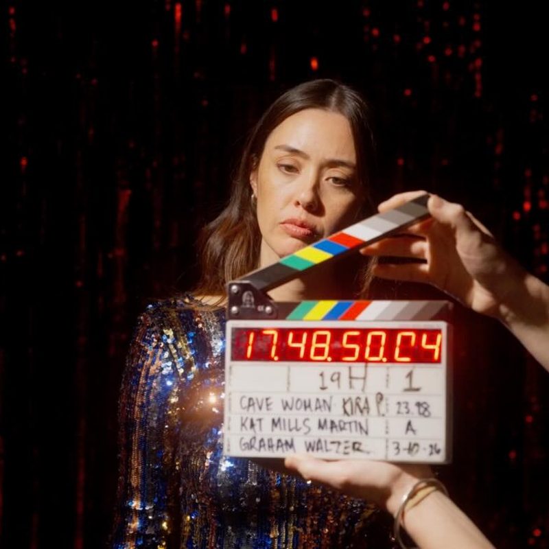 Kat holding a clapperboard on set