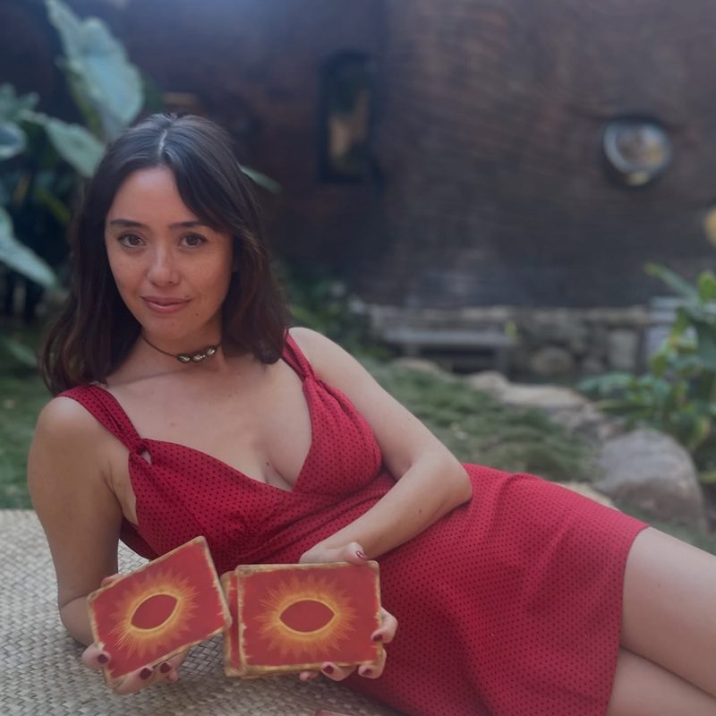 Kat in a red dress with tarot cards